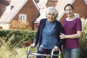 Daughter Helping Senior Mother To Use Walking Frame